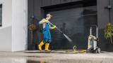A man pressure washing a garage door.