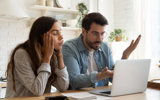 Confused couple looking at a laptop