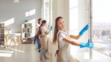 A woman cleaning a window smiling at the camera.